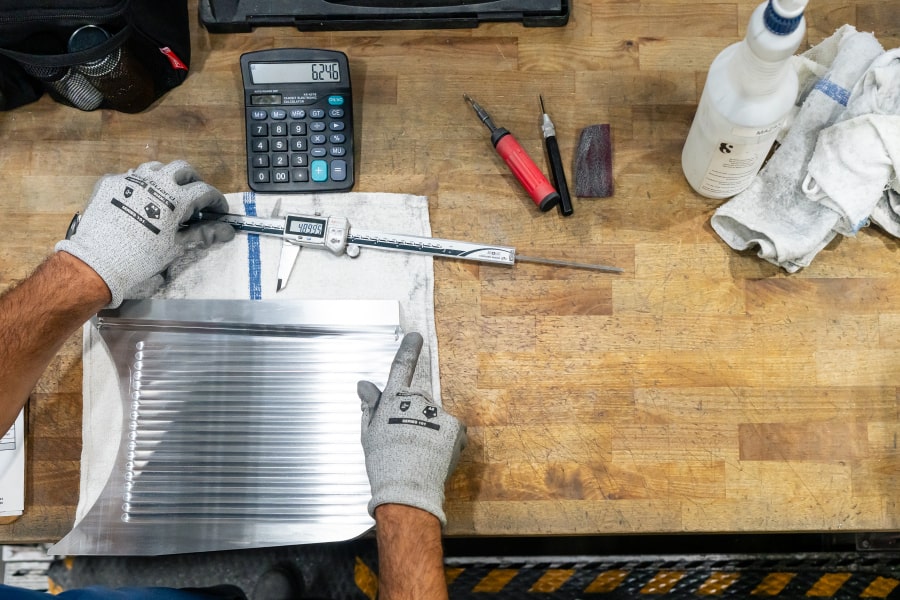 An individual performing metal gauge conversion by hand using a calculator.